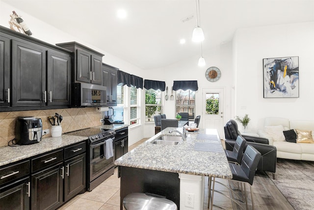 kitchen featuring decorative light fixtures, sink, a breakfast bar area, a kitchen island with sink, and stainless steel appliances