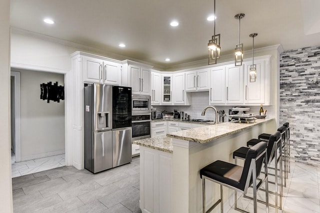 kitchen featuring a breakfast bar area, light stone counters, white cabinetry, hanging light fixtures, and stainless steel appliances