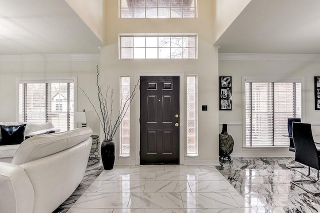 entryway featuring crown molding, a wealth of natural light, and a towering ceiling