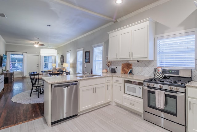 kitchen with sink, hanging light fixtures, stainless steel appliances, white cabinets, and kitchen peninsula