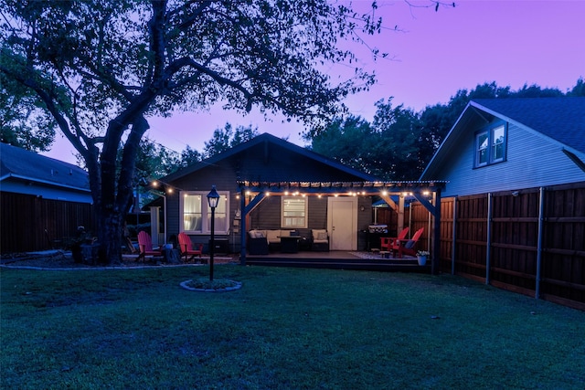 back house at dusk with a wooden deck and a yard