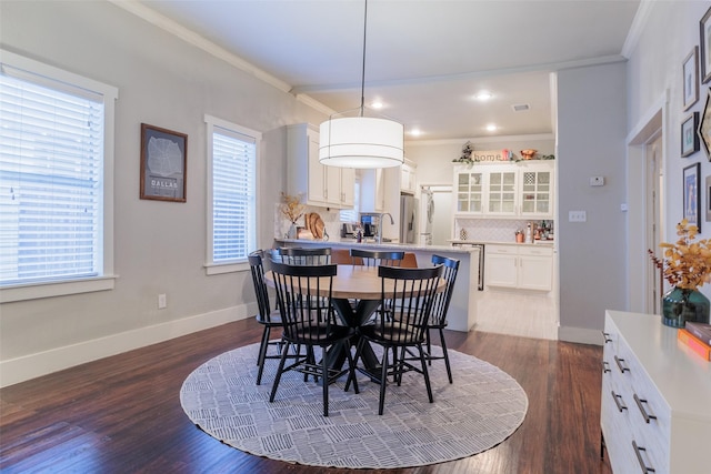 dining area with sink, crown molding, and dark hardwood / wood-style floors