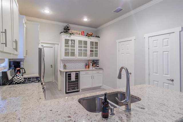 kitchen featuring wine cooler, sink, light stone counters, stainless steel appliances, and white cabinets