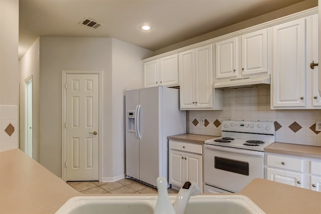 kitchen with light tile patterned floors, white cabinets, white appliances, and decorative backsplash