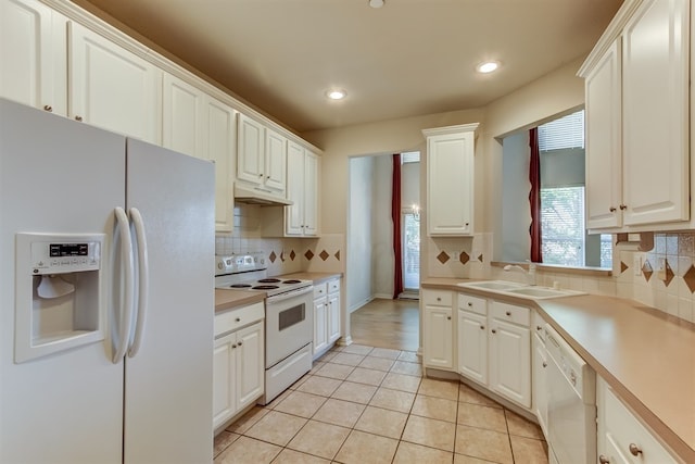 kitchen featuring sink, backsplash, white cabinets, light tile patterned floors, and white appliances