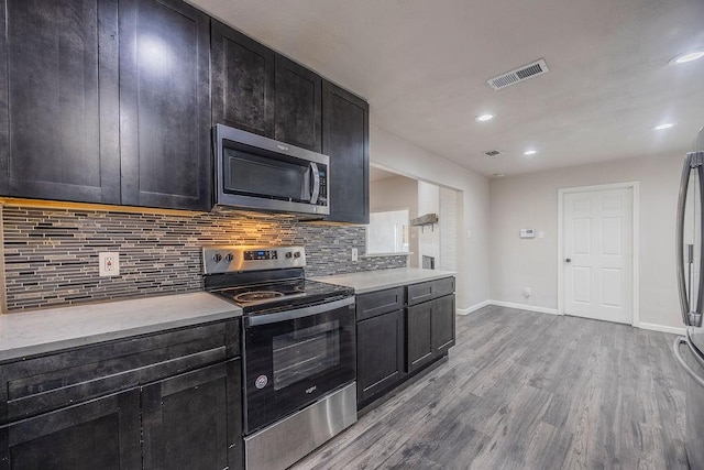 kitchen featuring appliances with stainless steel finishes, decorative backsplash, and light wood-type flooring