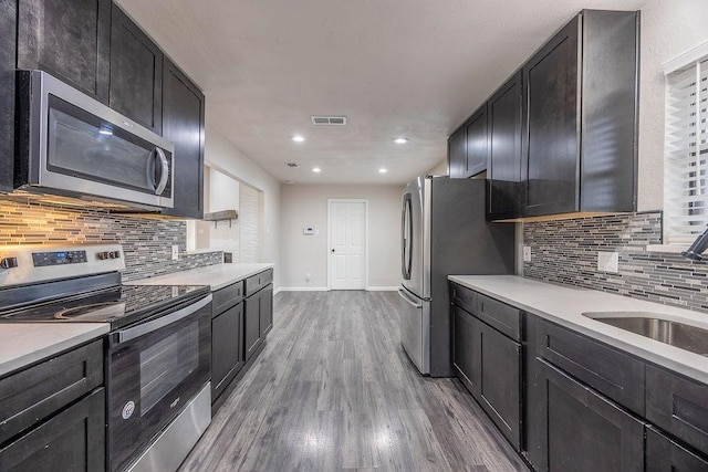 kitchen with hardwood / wood-style flooring, appliances with stainless steel finishes, sink, and backsplash