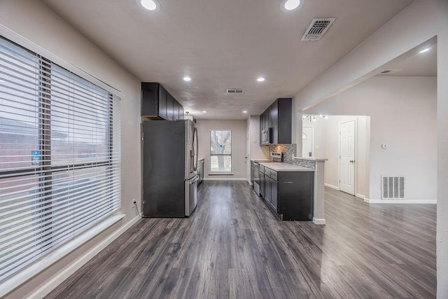 kitchen featuring appliances with stainless steel finishes, dark hardwood / wood-style flooring, light stone countertops, and backsplash