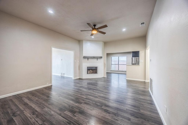 unfurnished living room featuring dark hardwood / wood-style floors, a large fireplace, and ceiling fan