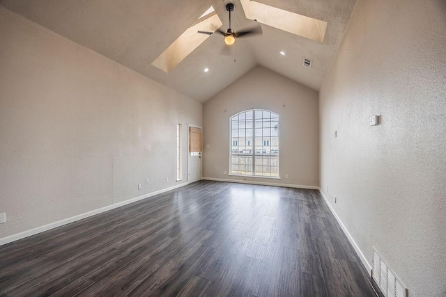 empty room with high vaulted ceiling, dark hardwood / wood-style floors, ceiling fan, and a skylight