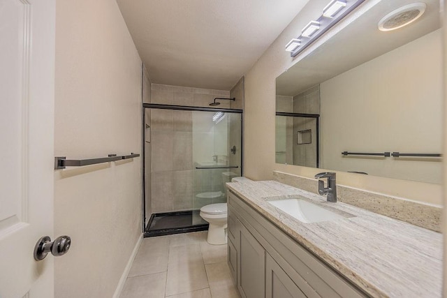 bathroom with vanity, a shower with shower door, tile patterned floors, and toilet