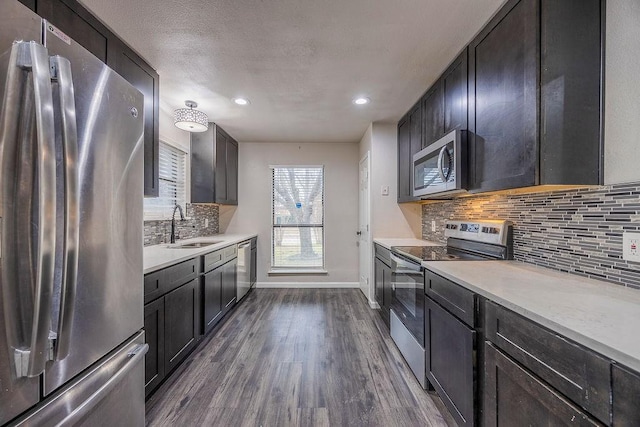 kitchen featuring appliances with stainless steel finishes, sink, decorative backsplash, dark wood-type flooring, and a textured ceiling