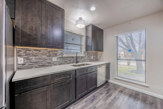 kitchen featuring sink, backsplash, light hardwood / wood-style floors, stainless steel appliances, and dark brown cabinets