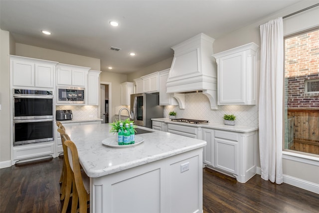 kitchen featuring white cabinetry, appliances with stainless steel finishes, and an island with sink