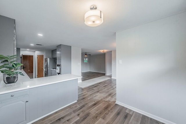 kitchen with hardwood / wood-style flooring, ceiling fan, stainless steel fridge, gray cabinets, and kitchen peninsula