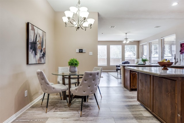 dining space featuring ceiling fan with notable chandelier and light wood-type flooring