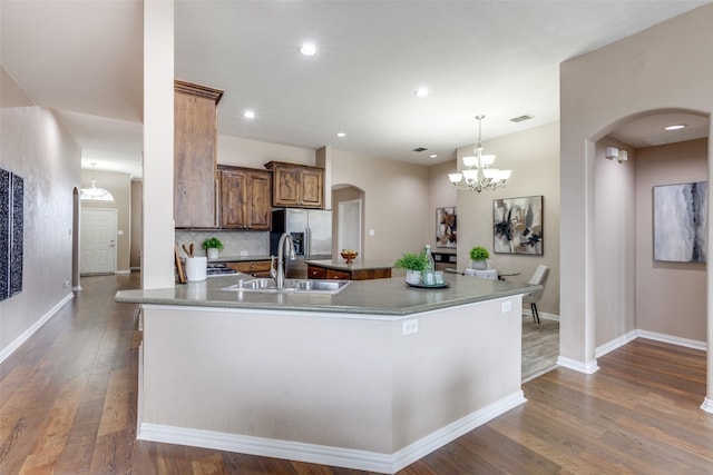 kitchen with sink, dark hardwood / wood-style flooring, kitchen peninsula, pendant lighting, and decorative backsplash