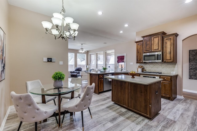 kitchen with pendant lighting, stainless steel appliances, a center island, tasteful backsplash, and kitchen peninsula