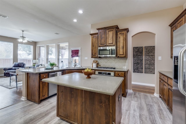 kitchen with a kitchen island, sink, decorative backsplash, kitchen peninsula, and stainless steel appliances