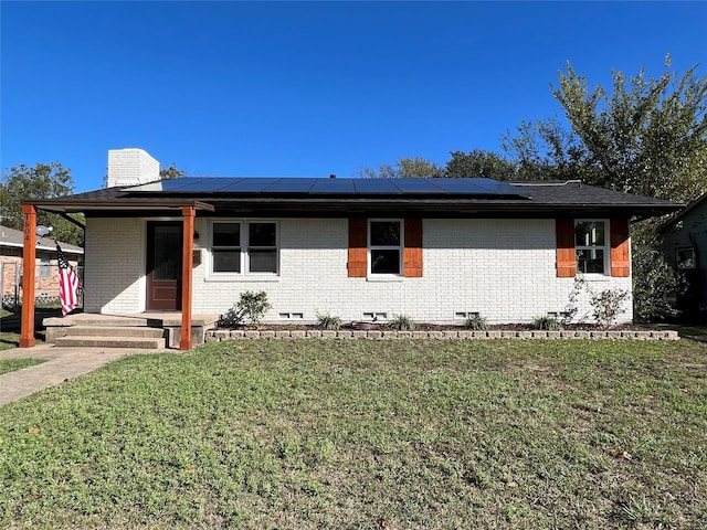 view of front of property featuring a front lawn and solar panels