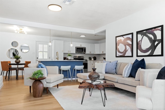 living room featuring sink and light hardwood / wood-style floors