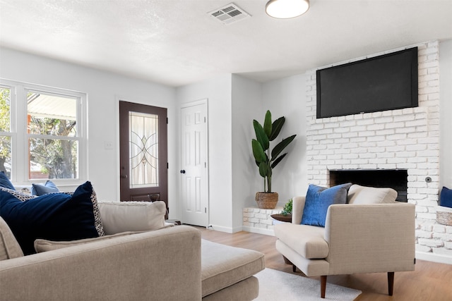 living room featuring light hardwood / wood-style floors and a brick fireplace