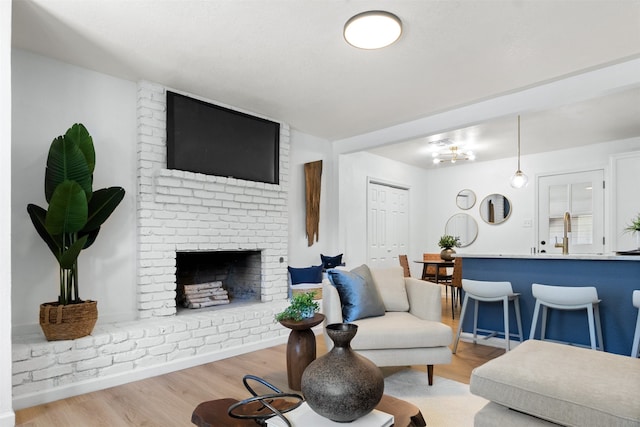 living room with a brick fireplace and light hardwood / wood-style flooring