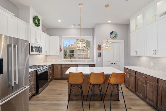 kitchen with a kitchen bar, a kitchen island, white cabinets, and appliances with stainless steel finishes