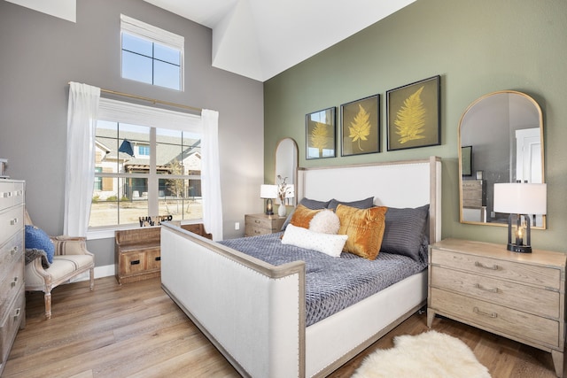 bedroom with a towering ceiling, multiple windows, and light wood-type flooring