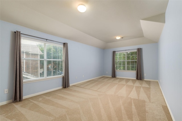 unfurnished room featuring lofted ceiling and light colored carpet