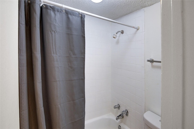 bathroom with shower / bath combo with shower curtain, a textured ceiling, and toilet