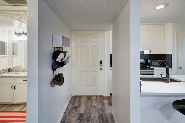 entryway featuring sink, a textured ceiling, and light wood-type flooring