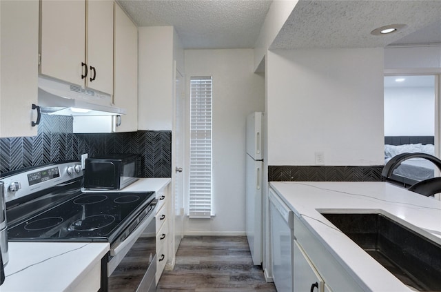 kitchen with sink, white appliances, dark wood-type flooring, a textured ceiling, and white cabinets