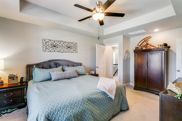 bedroom featuring ceiling fan, light colored carpet, and a raised ceiling