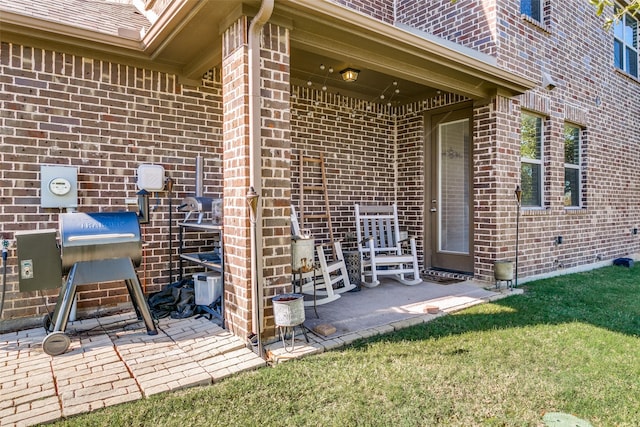 view of exterior entry with a yard and a patio area