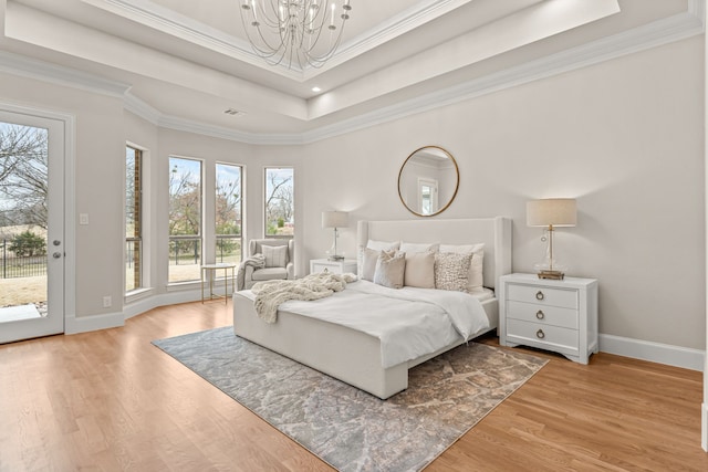 bedroom featuring light hardwood / wood-style flooring, crown molding, access to outside, and a raised ceiling