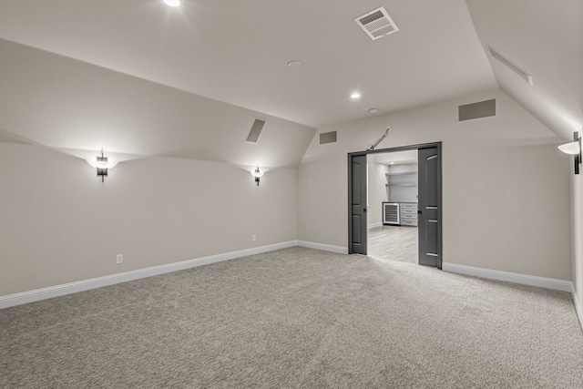 bonus room with lofted ceiling and light carpet