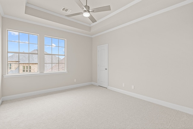 carpeted empty room featuring a tray ceiling, ornamental molding, and ceiling fan