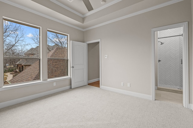 carpeted spare room featuring a tray ceiling, crown molding, and ceiling fan