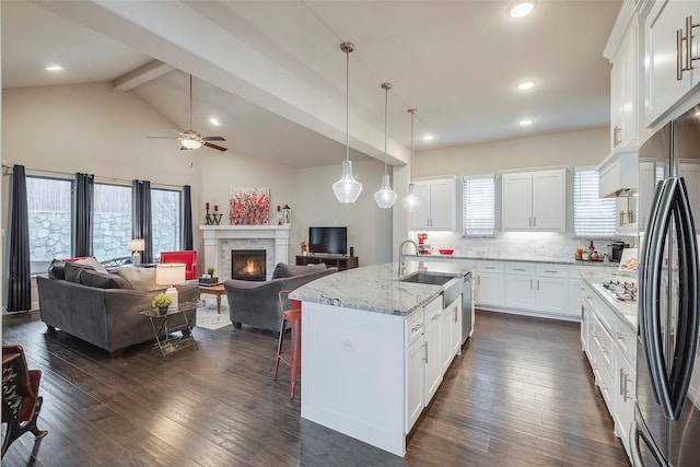 kitchen featuring dark wood-style flooring, a fireplace, backsplash, appliances with stainless steel finishes, and open floor plan