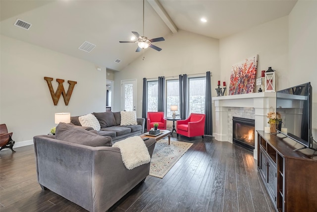 living room featuring a stone fireplace, dark hardwood / wood-style floors, high vaulted ceiling, beamed ceiling, and ceiling fan