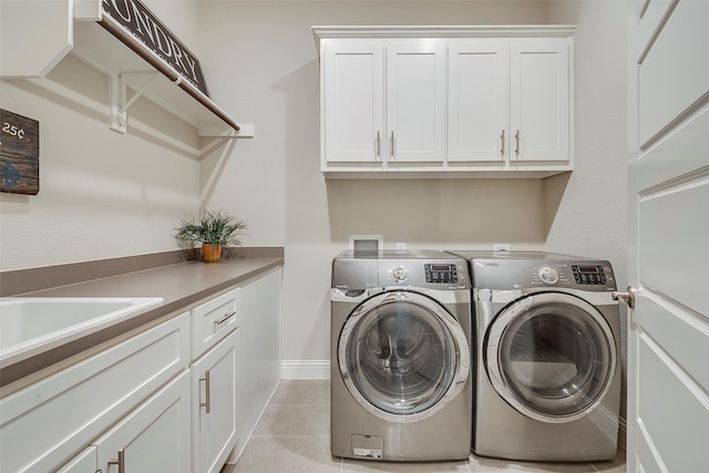 clothes washing area with cabinets, light tile patterned flooring, washer and dryer, and sink