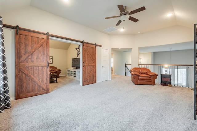 unfurnished room with vaulted ceiling, a barn door, ceiling fan, and carpet