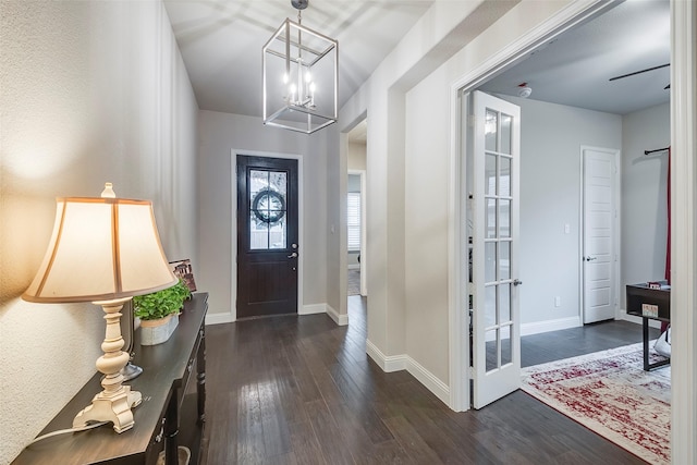 entryway with a chandelier, dark wood finished floors, and baseboards