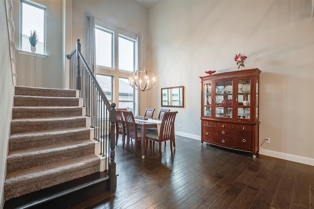 dining area featuring dark hardwood / wood-style flooring, an inviting chandelier, a healthy amount of sunlight, and a high ceiling