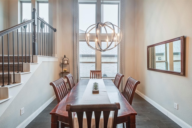 dining area featuring a notable chandelier, a towering ceiling, and dark wood-type flooring