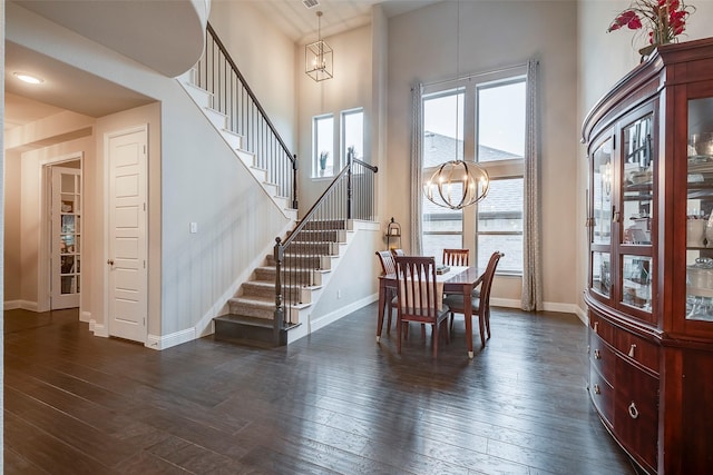 dining room with a notable chandelier, a high ceiling, baseboards, stairway, and dark wood-style floors