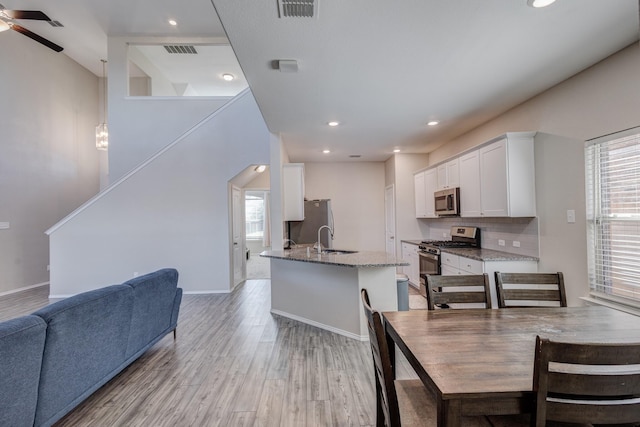 dining area with sink, a wealth of natural light, light hardwood / wood-style flooring, and ceiling fan