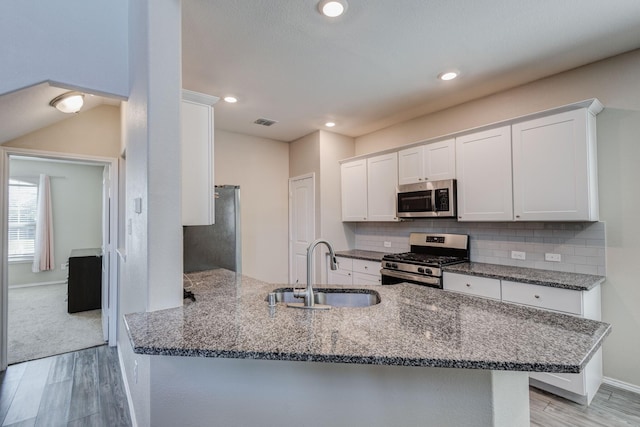 kitchen featuring sink, appliances with stainless steel finishes, dark stone countertops, backsplash, and white cabinets