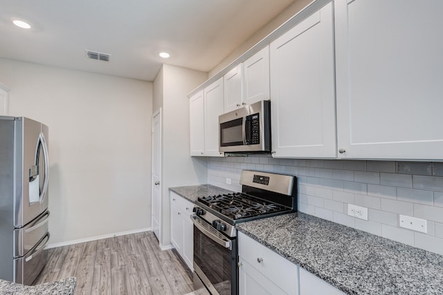 kitchen with appliances with stainless steel finishes, white cabinets, stone countertops, decorative backsplash, and light wood-type flooring